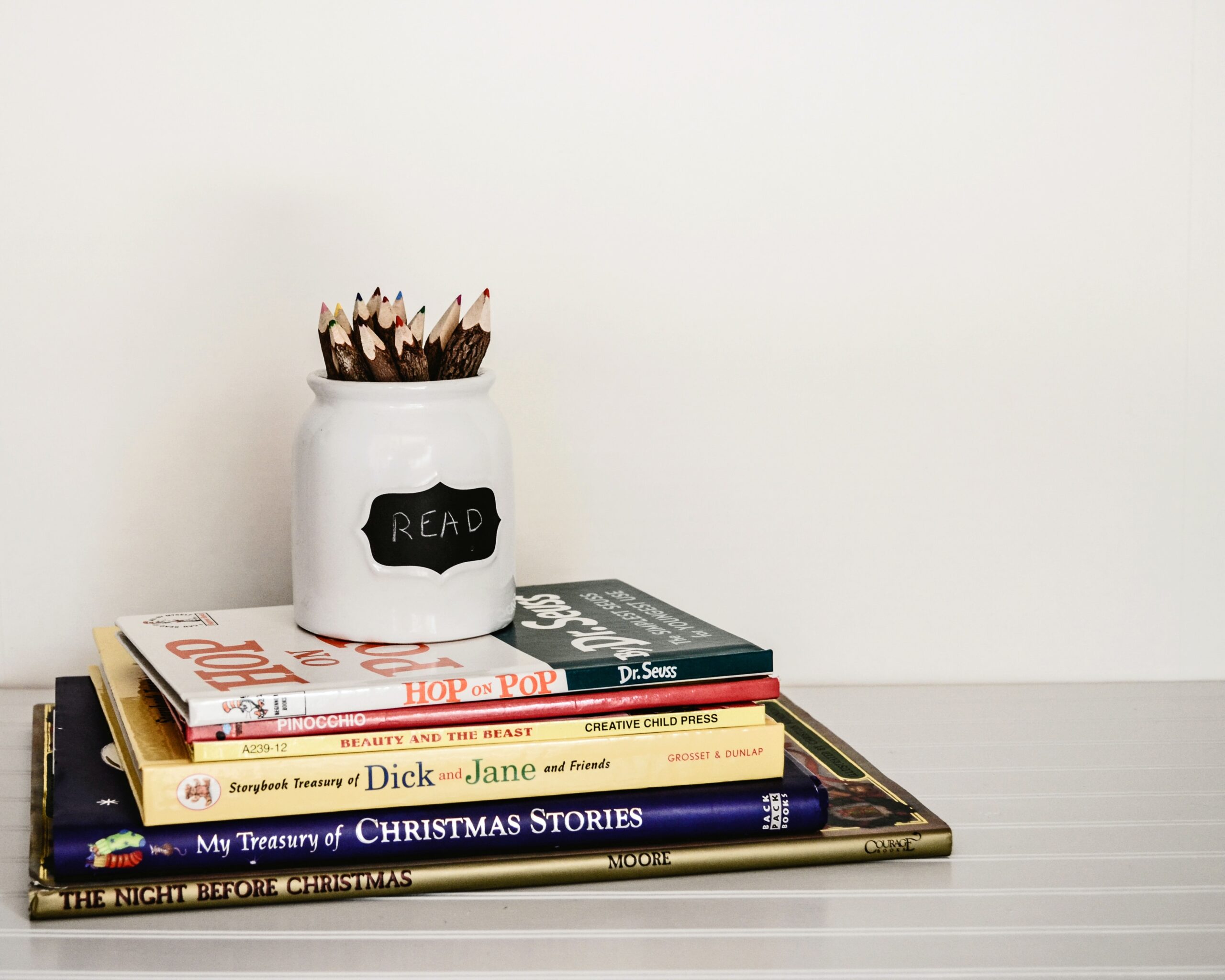 Stack of books with ceramic pencil jar The Benefits of a Read-A-Thon photo by Debby Hudson on Unsplash